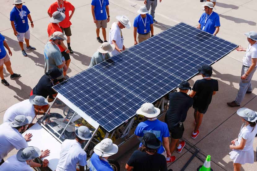 Students across teams work together to move a solar car with mechanical troubles off a...