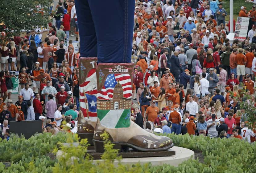 Texas and Oklahoma fans walk past the boots of Big Tex as they make their way to the stadium...