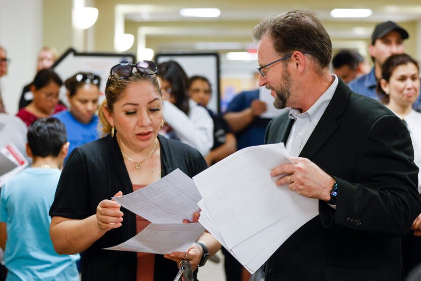 Carrolton-Farmers Branch area associate superintendent Brian Moersch hands information to...