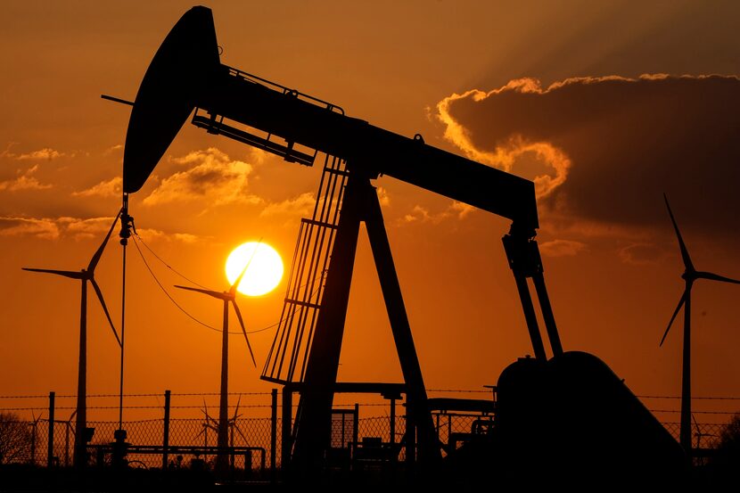 FILE - A pump jack extracts crude oil at an oil field near wind turbines in Emlichheim,...