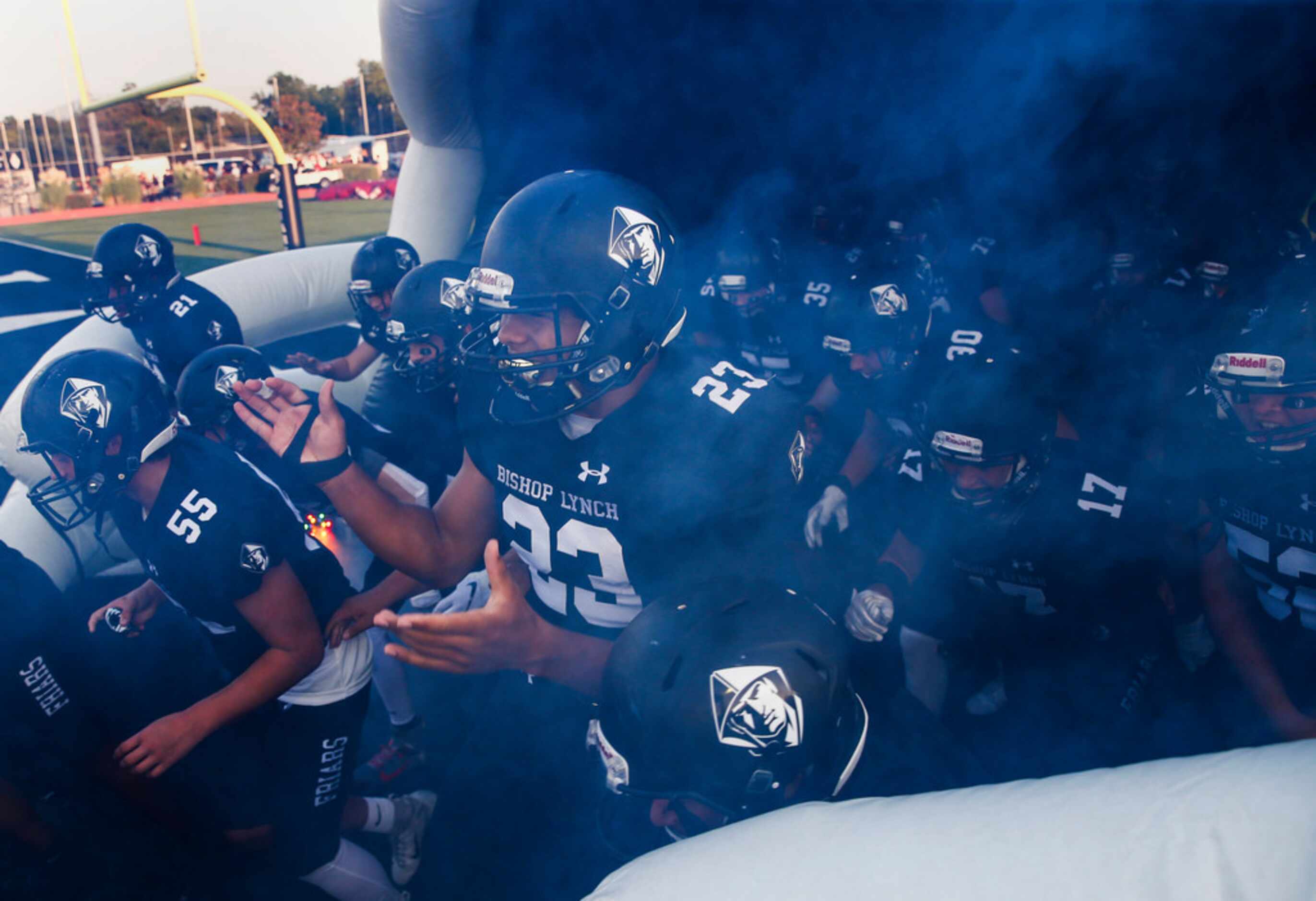 The Bishop Lynch Friars break onto the field prior to a high school football game between...
