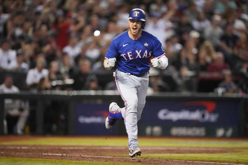 Texas Rangers designated hitter Mitch Garver celebrates a RBI single, scoring Corey Seager,...