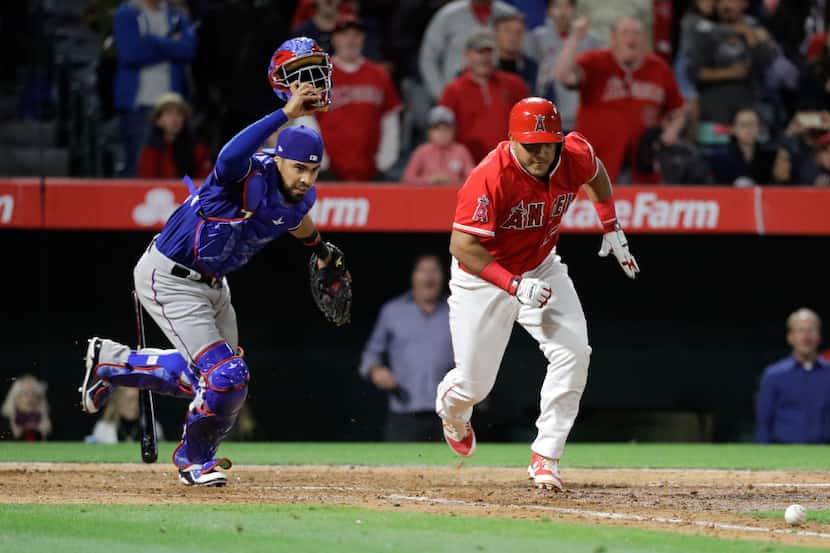 Los Angeles Angels' Carlos Perez, right, runs to first base after hitting a walk-off bunt as...