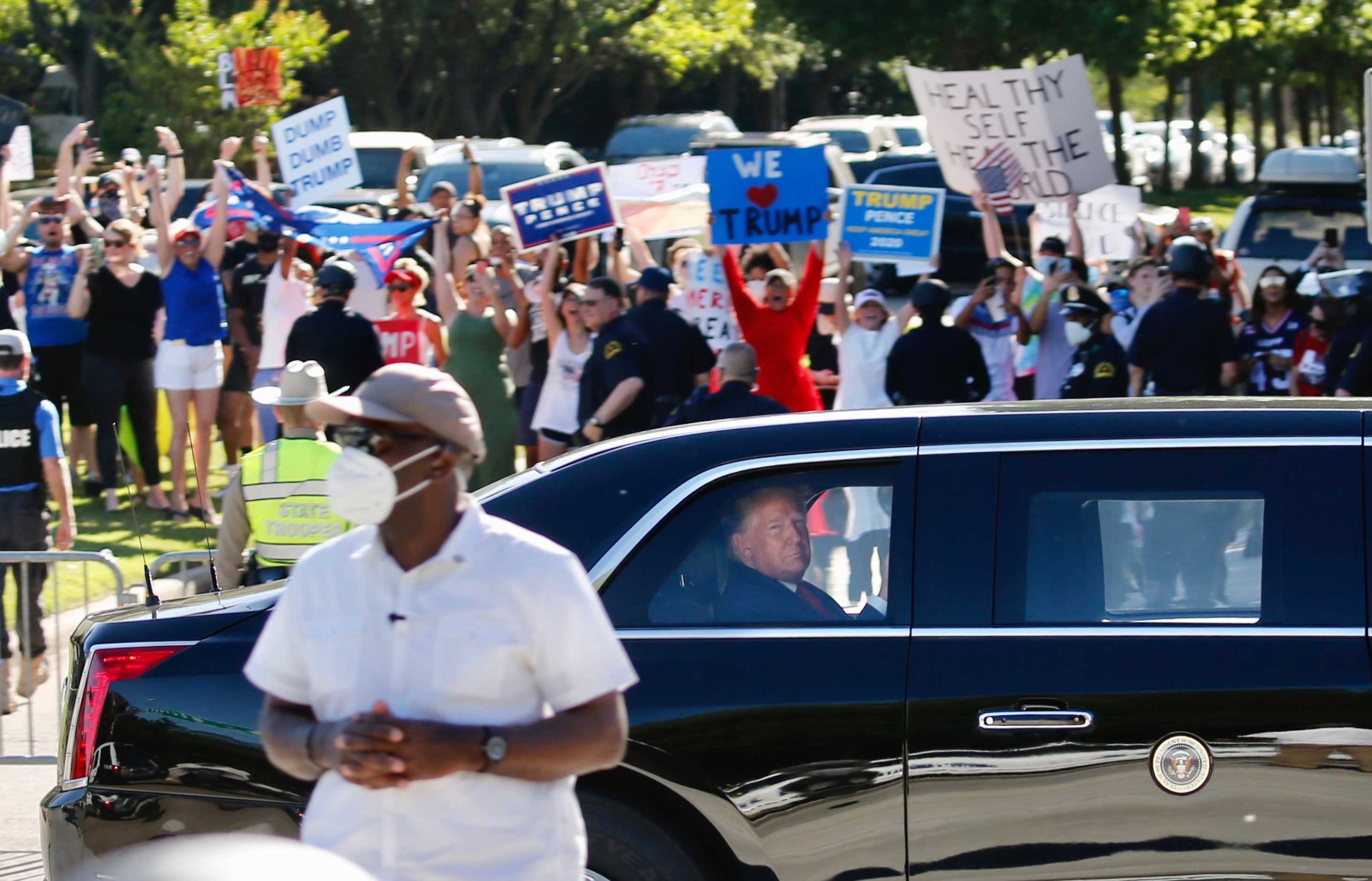 Supporters and detractors line the road as President Donald Trump rides in “The Beast,” the...