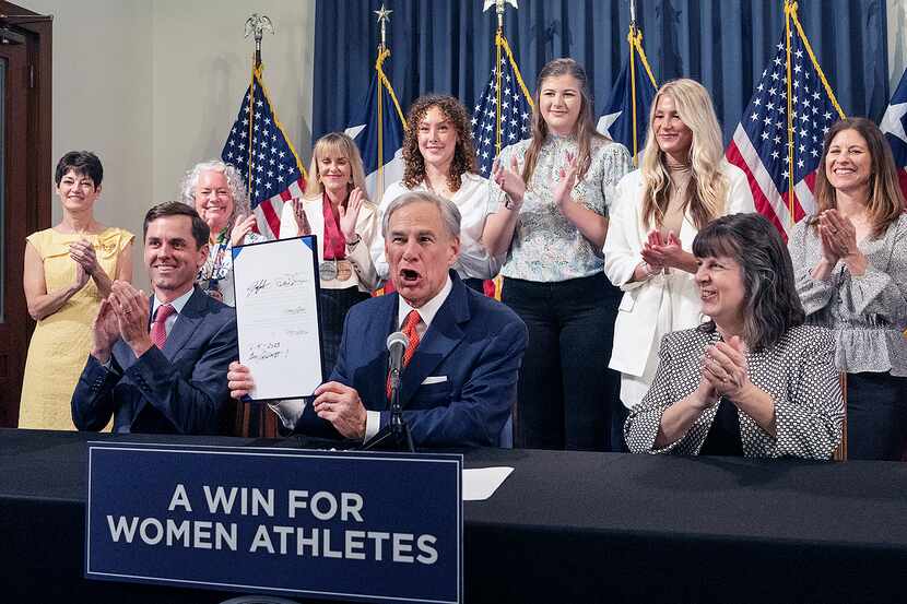 Texas Gov. Greg Abbott holds up Senate Bill 15 after signing it into law during a bill...