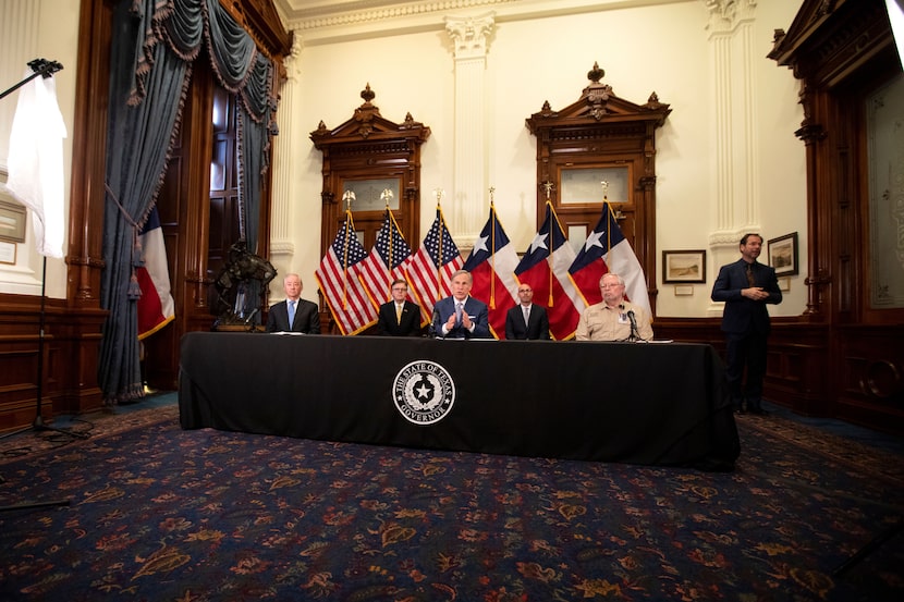 As Gov. Greg Abbott (center) spoke about lifting some coronavirus-spurred restrictions,...