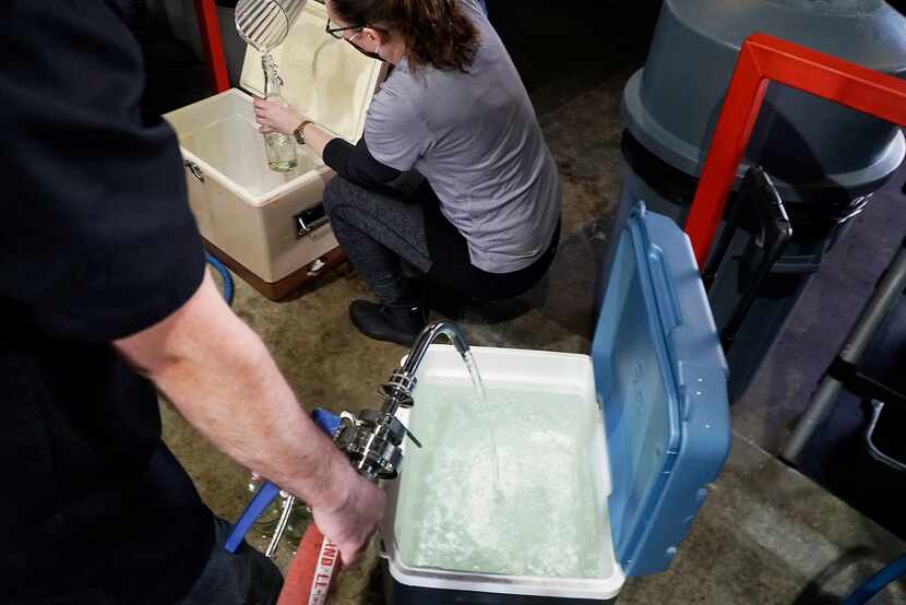 Employees fill a container with filtered water at Cowtown Brewing Co. in Fort Worth.

