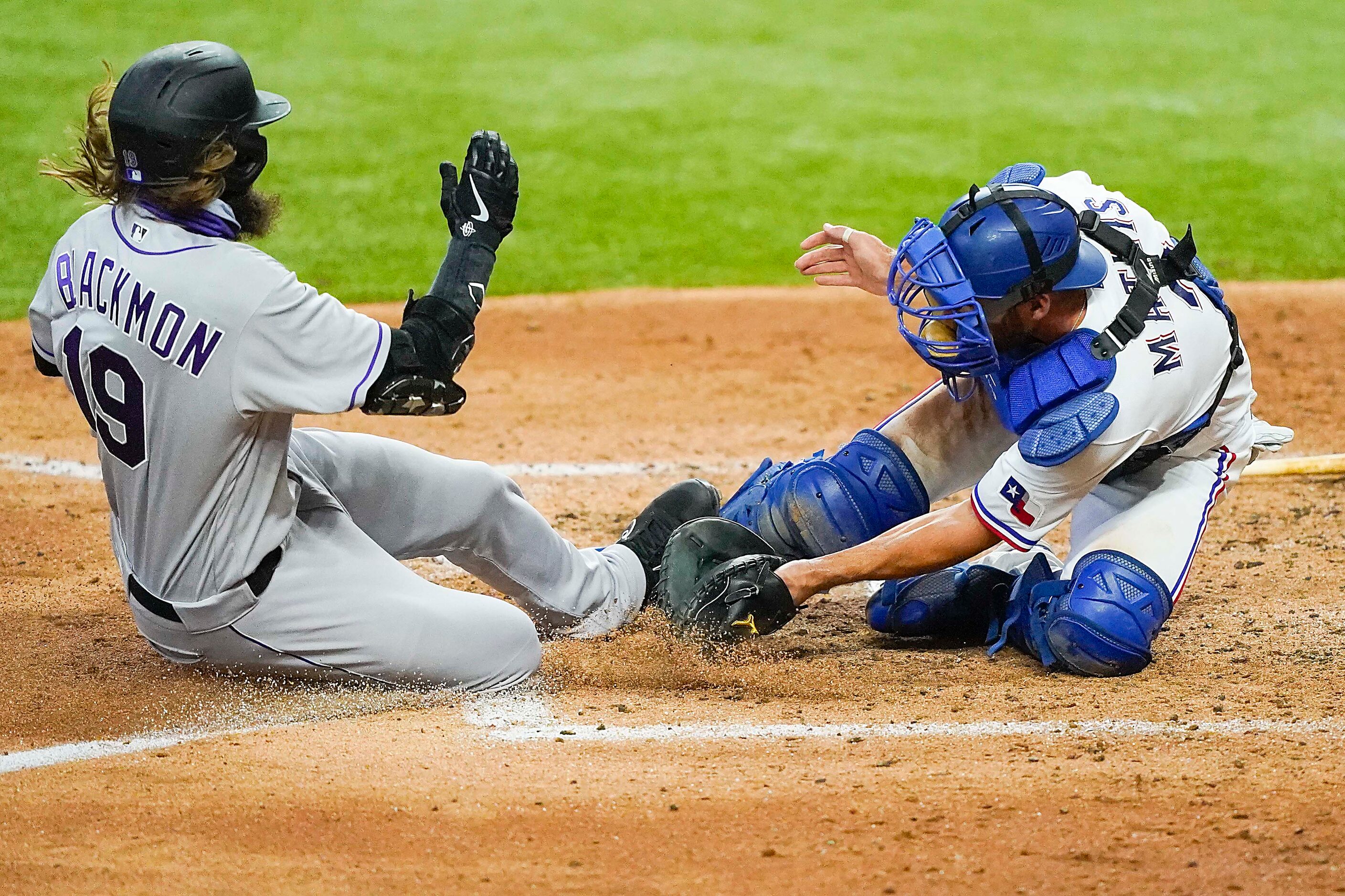 Colorado Rockies outfielder Charlie Blackmon is safe at home as the ball gets away from...