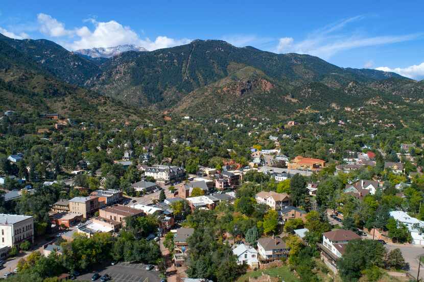 Pikes Peak looms behind the town of Manitou Springs, Colo. The famous Pikes Peak Cog Railway...