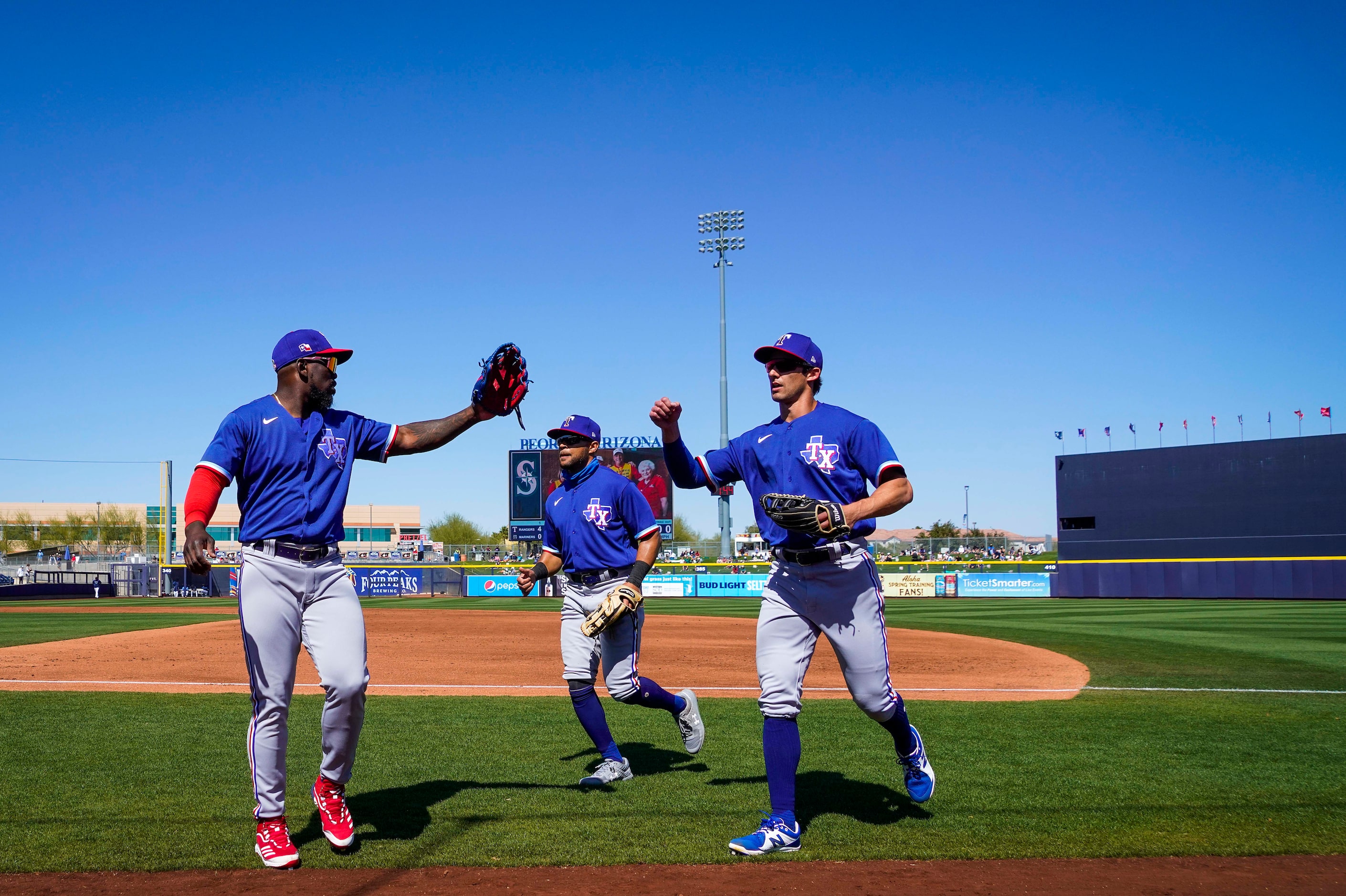 Texas Rangers center fielder Eli White (right) gets a hand from right fielder Adolis García...