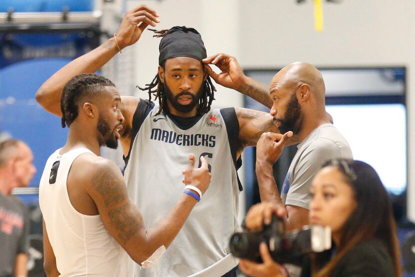 Dallas Mavericks center DeAndre Jordan (center) listens in on a conversation with assistant...