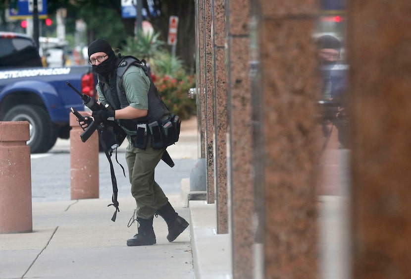 An armed shooter outside the Earle Cabell Federal Building looks in the direction of Dallas...