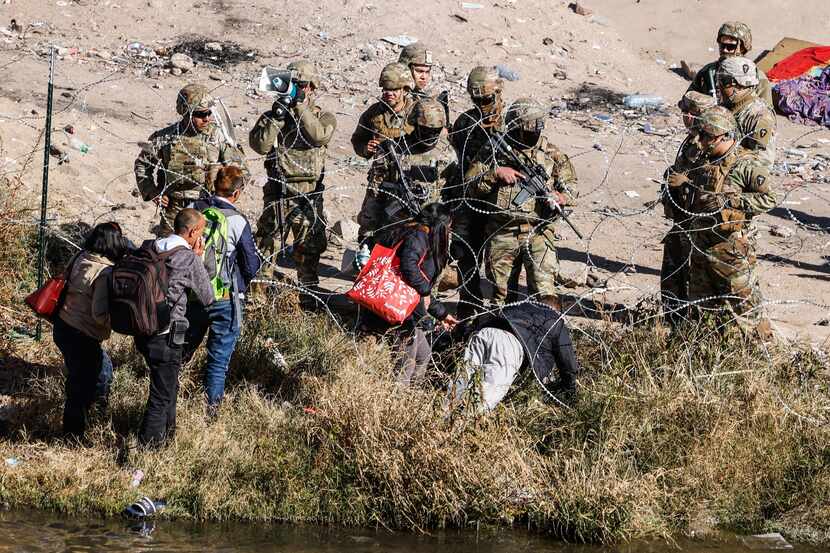 A group of migrants defy the orders of the Texas National Guard not to cross the Rio Grande...
