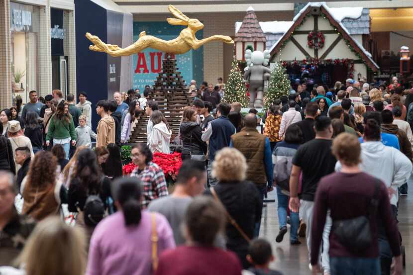Shoppers walk on the first floor of NorthPark Center browsing storefronts during Black...