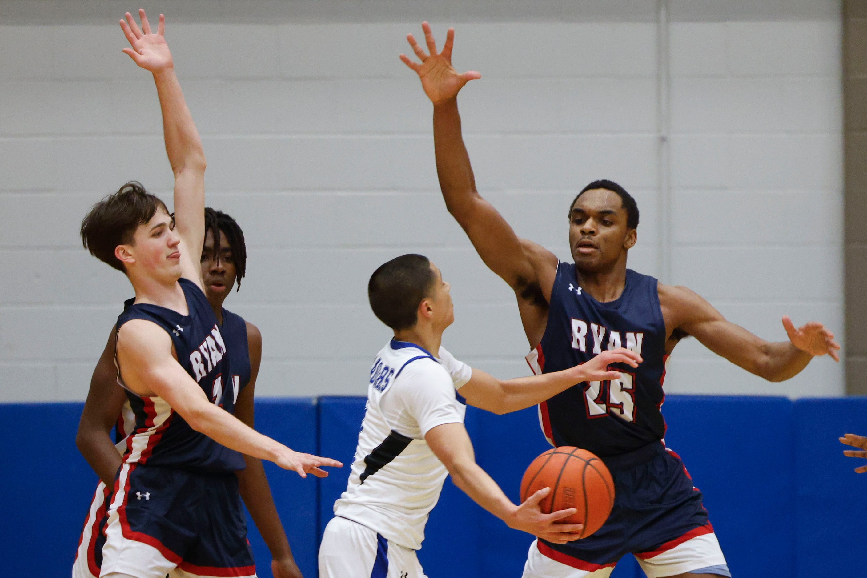 Mansfield Summit’s Theo Brannan (center) looks to shoot past Denton Ryan’s Scottie Johnson...