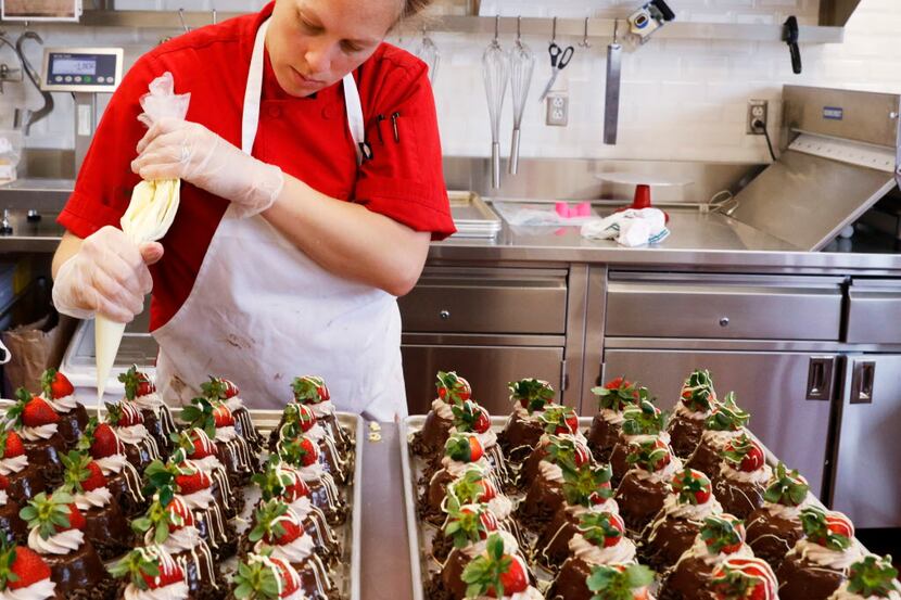Carrie Castano, cake decorator, puts the finishing touches on chocolate moose cakes at...