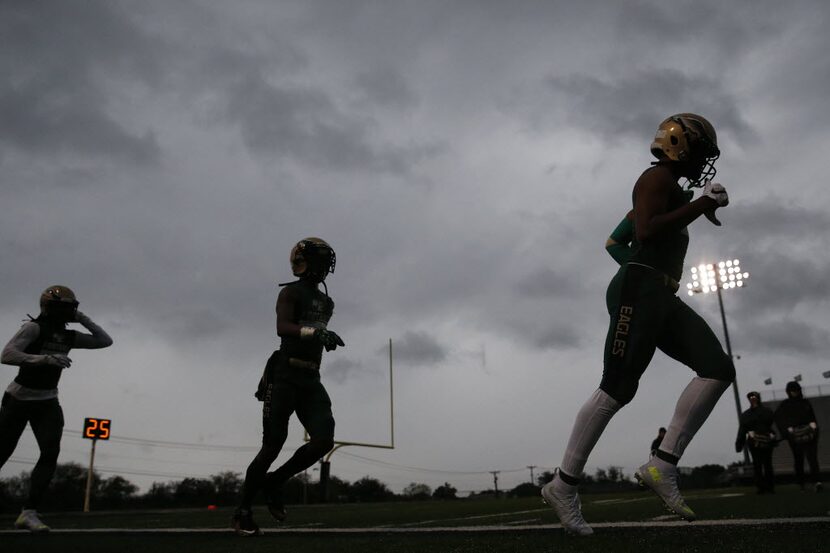 DeSoto players run into the locker room in between rain showers before a high school...