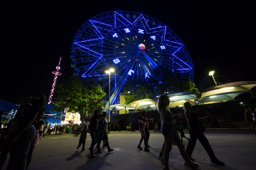 Festival goers walk pass the Texas Star Ferris wheel during the free festival celebrating...