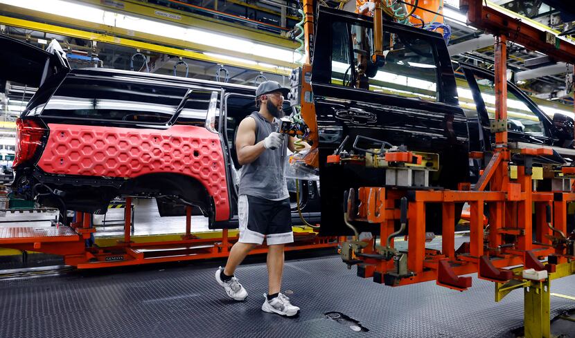 Assembly team worker Jalon Hogan uses a machine to move a rear door to a large SUV at the...