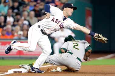 Oakland Athletics' Khris Davis, right, slides safely into third base on a wild pitch thrown...