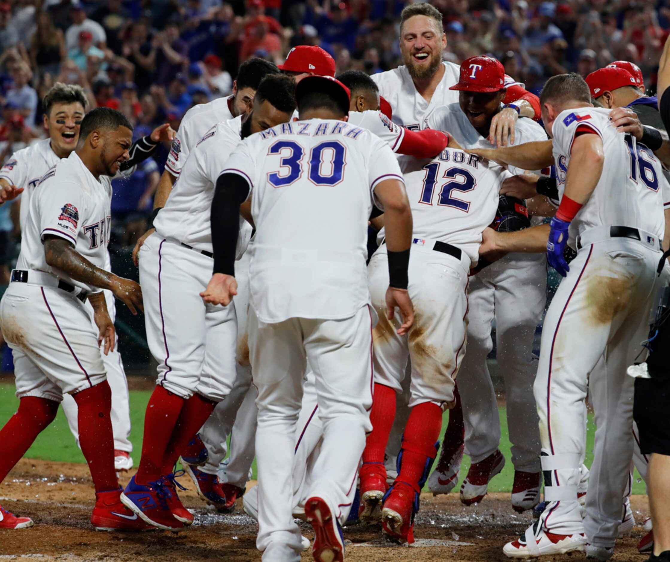 The Texas Rangers celebrate with Rougned Odor (12), who touches the plate after hitting a...