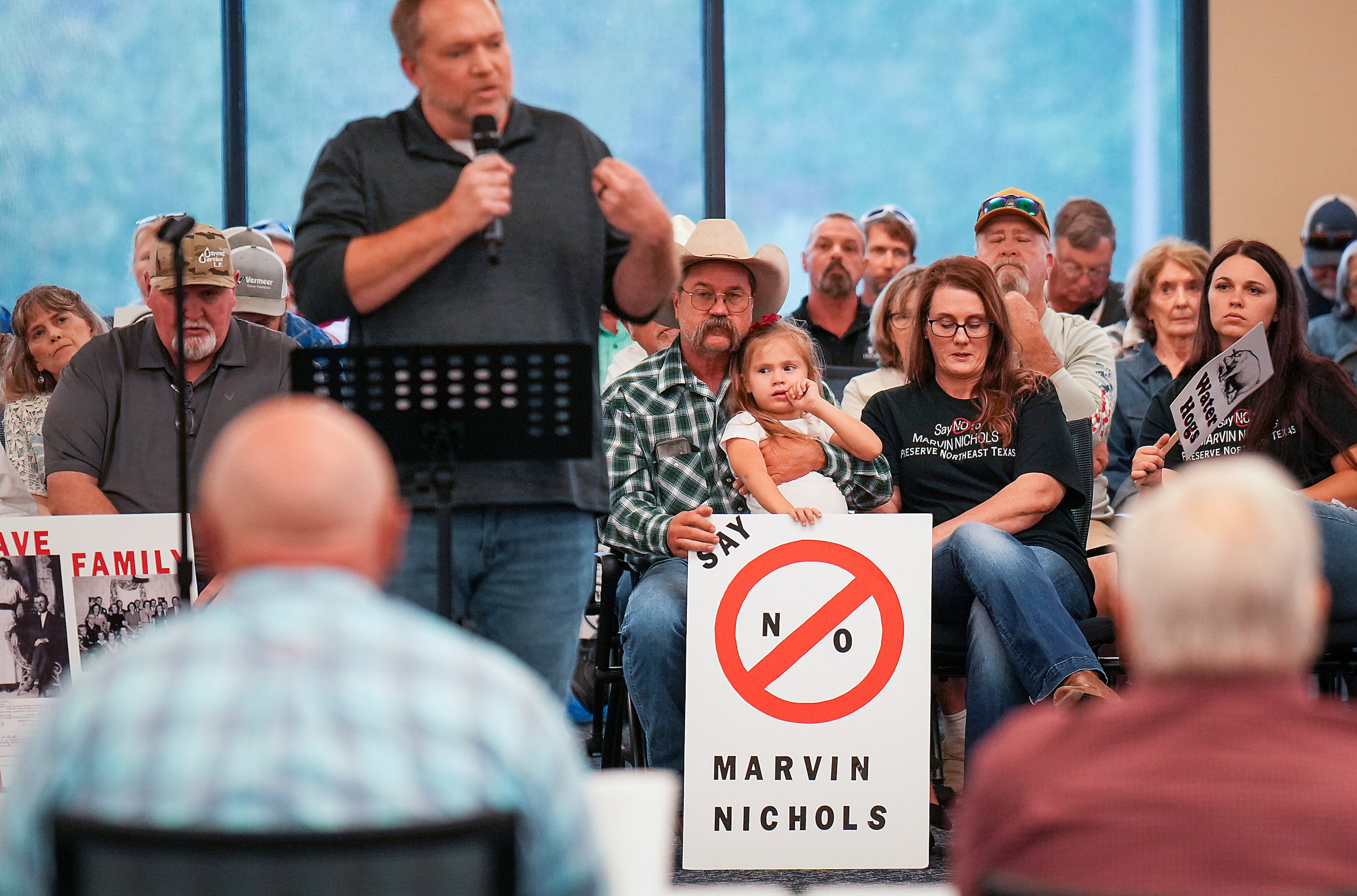 Casey Conway holds his granddaughter Novalee Martinez, and a sign in opposition to the...