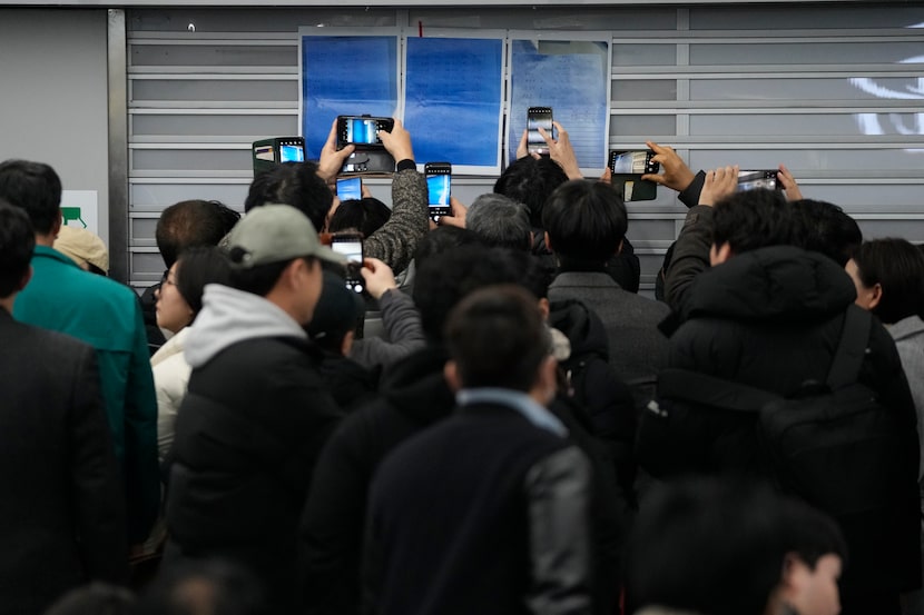 Relatives take photos of passenger lists at Muan International Airport in Muan, South Korea,...