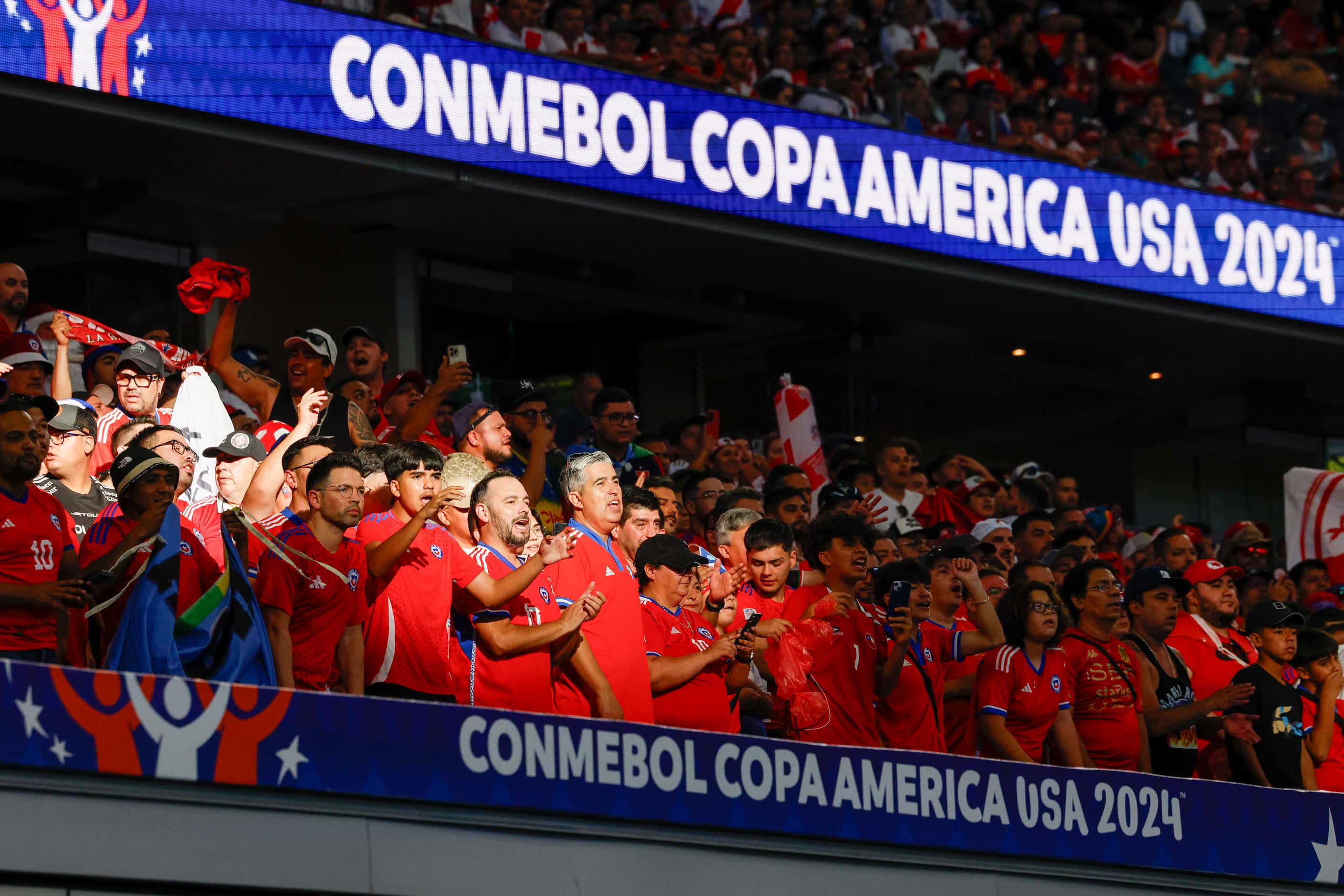 Chile fans stand and cheer in the sunlight during the first half of a Copa America Group A...