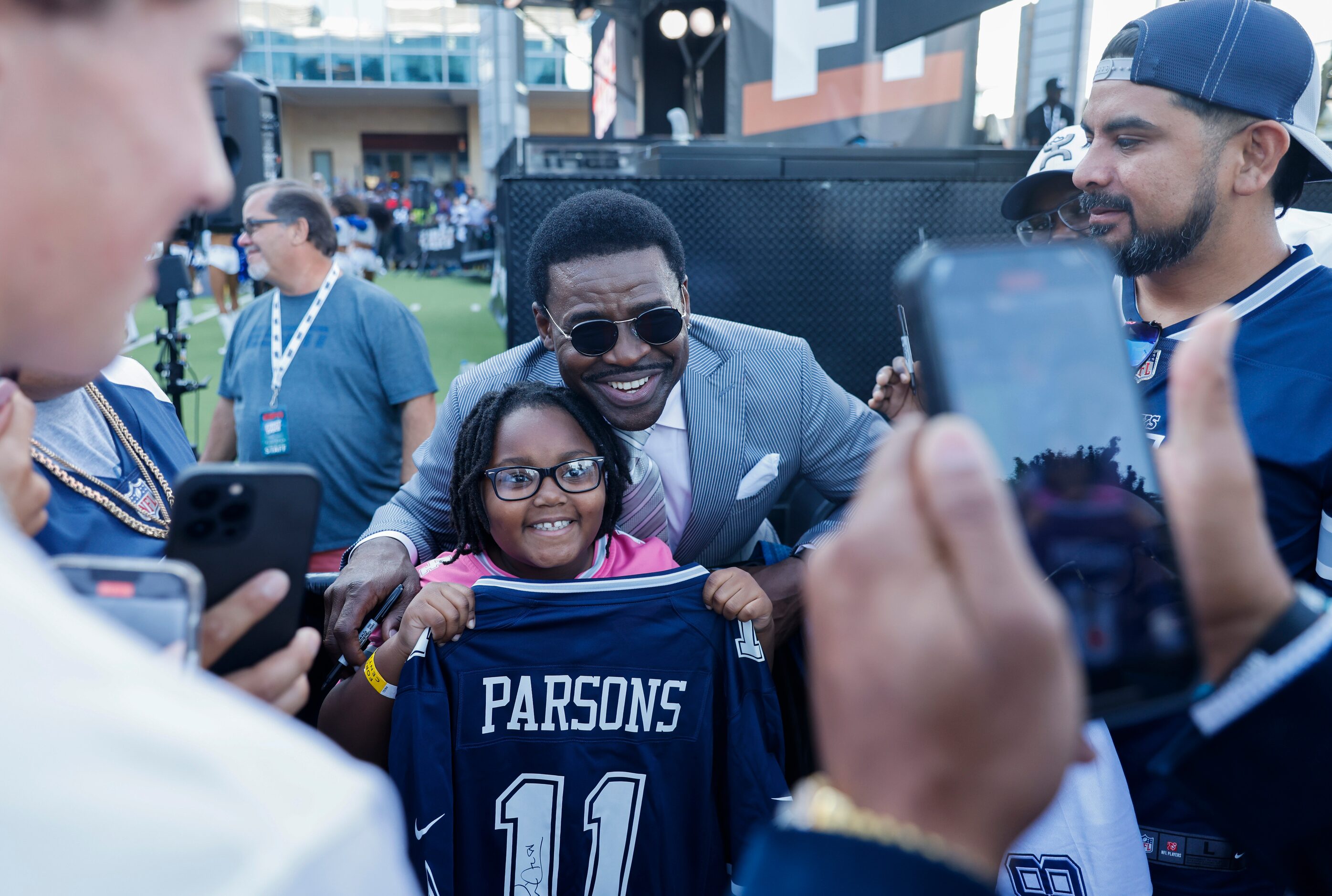 Former Dallas Cowboys player Michael Irvin, back, takes a photo with Alyannah Spearman, 8,...