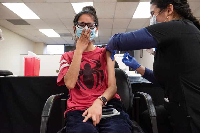Ana Beatriz, 24, of Alvarado, touches her mask as she yelps while receiving a COVID-19...