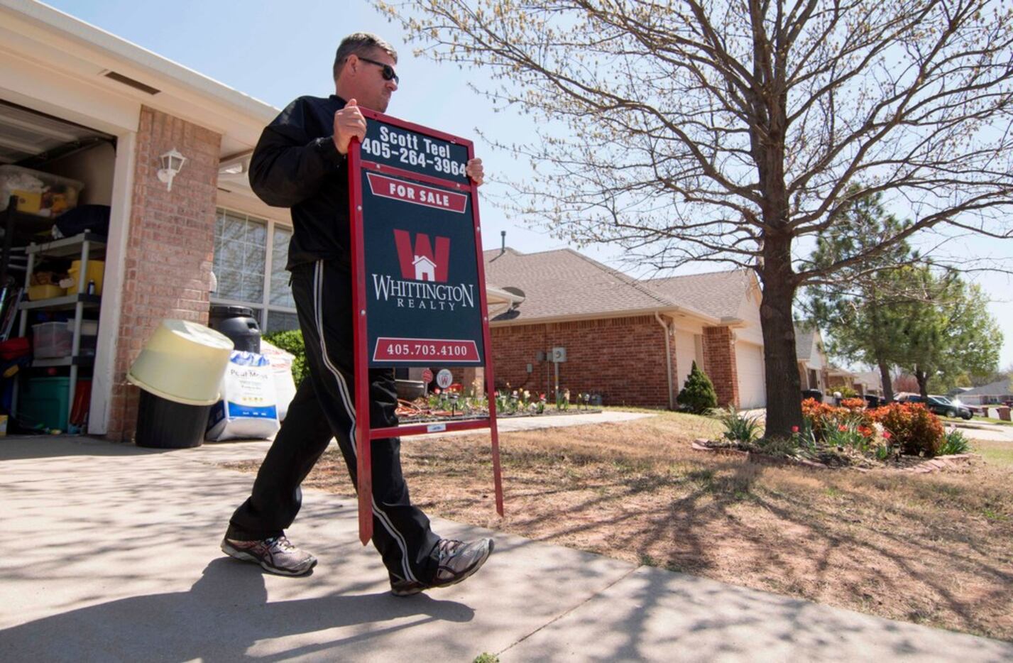 Scott Teel, a high school history teacher in Moore, Okla., carries a 'for sale' sign, as...