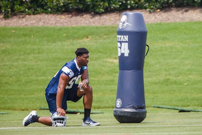 Dallas Cowboys defensive tackle David Irving kneels to the side and watches teammates...