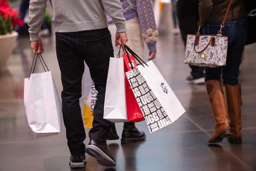 A male shopper carries bags as he walks with family inside NorthPark Center during Black...