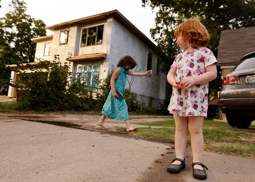 Opal Benjamin, 2, watches as her sister Ivy, 6, plays in their front yard next door to a...