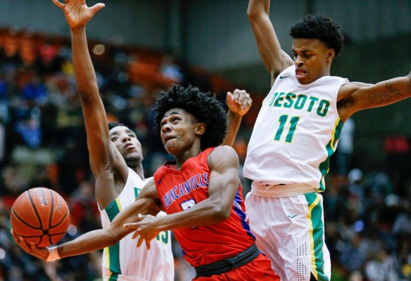 Duncanville junior guard Ja'Bryant Hill, center, attempts a layup as DeSoto senior guards...