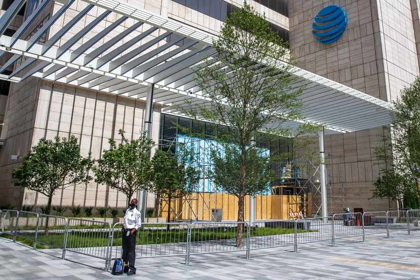 A security officer walks in front of the boarded-up headquarters of AT&T in downtown Dallas...