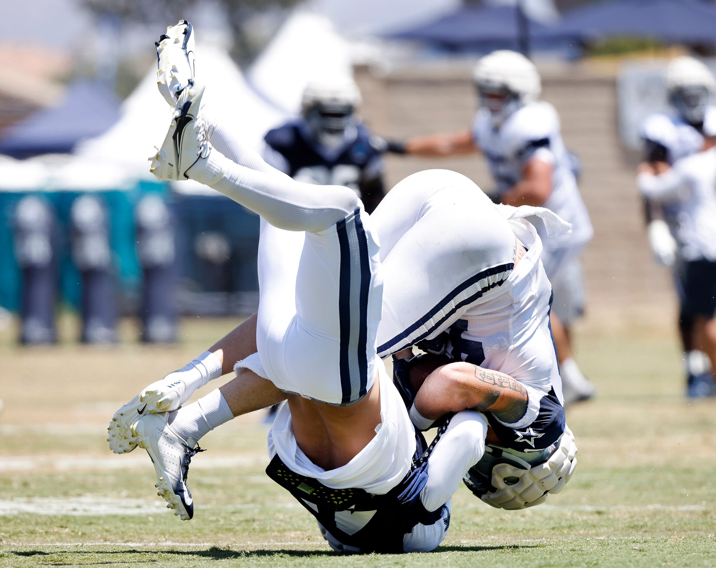 Dallas Cowboys linebacker Malik Jefferson (45, blue) rolls up and over as he tackles tight...