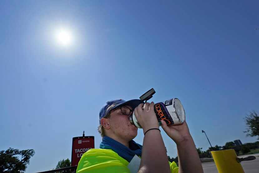 Jennifer Michener bebe agua mientras trabaja bajo el sol de Texas en un estacionamiento de...