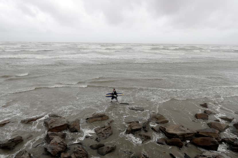 Mark Metzger carries his surfboard through the water in Galveston, Texas as Hurricane Harvey...