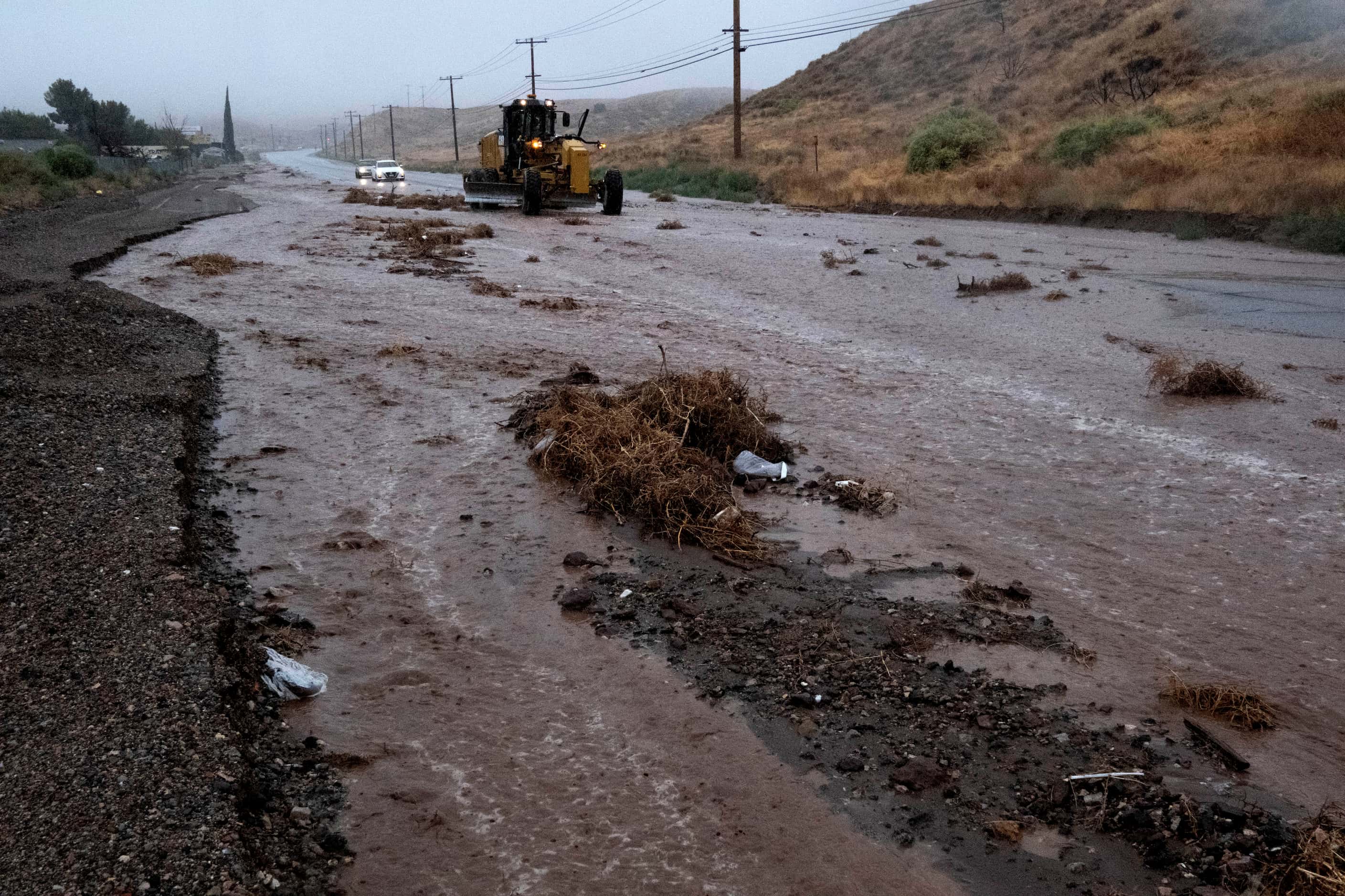 A plow clears debris along a flooded Sierra Highway in Palmdale, Calif., as Tropical Storm...