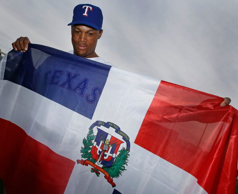 Texas third baseman Adrian Beltre poses with the Dominican Republic flag at photo day during...