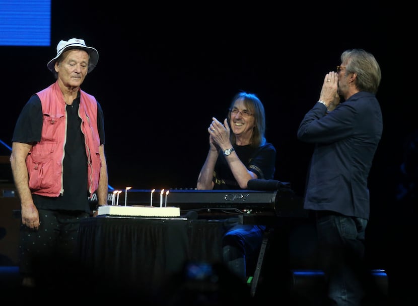 Eric Clapton (far right) presents a birthday cake to actor, comedian and event emcee Bill...