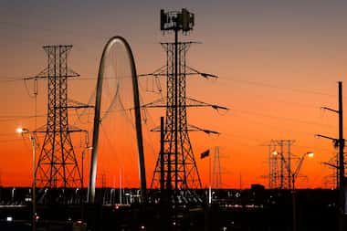 The Margaret Hunt Hill Bridge is seen behind high transmission power lines running along...