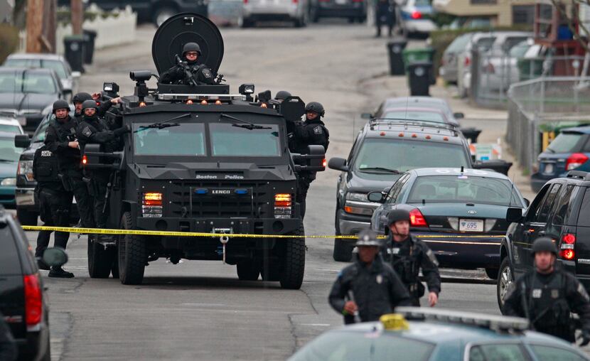 Police officers in tactical gear arrive on an armored vehicle as they surround an apartment...