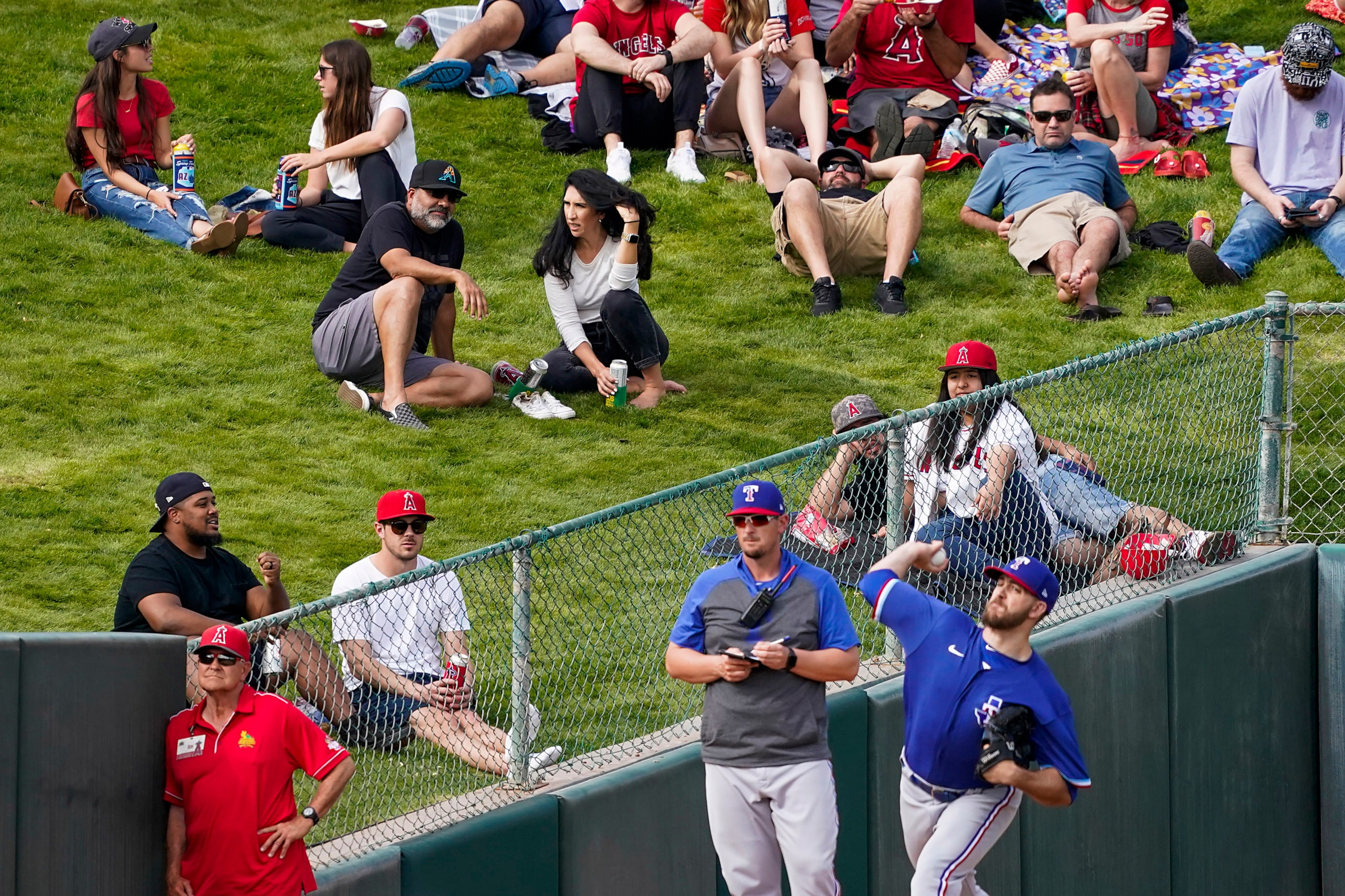 Fans on the outfield berm watch Texas Rangers pitcher Lake Lemoine warm up in the  bullpen...