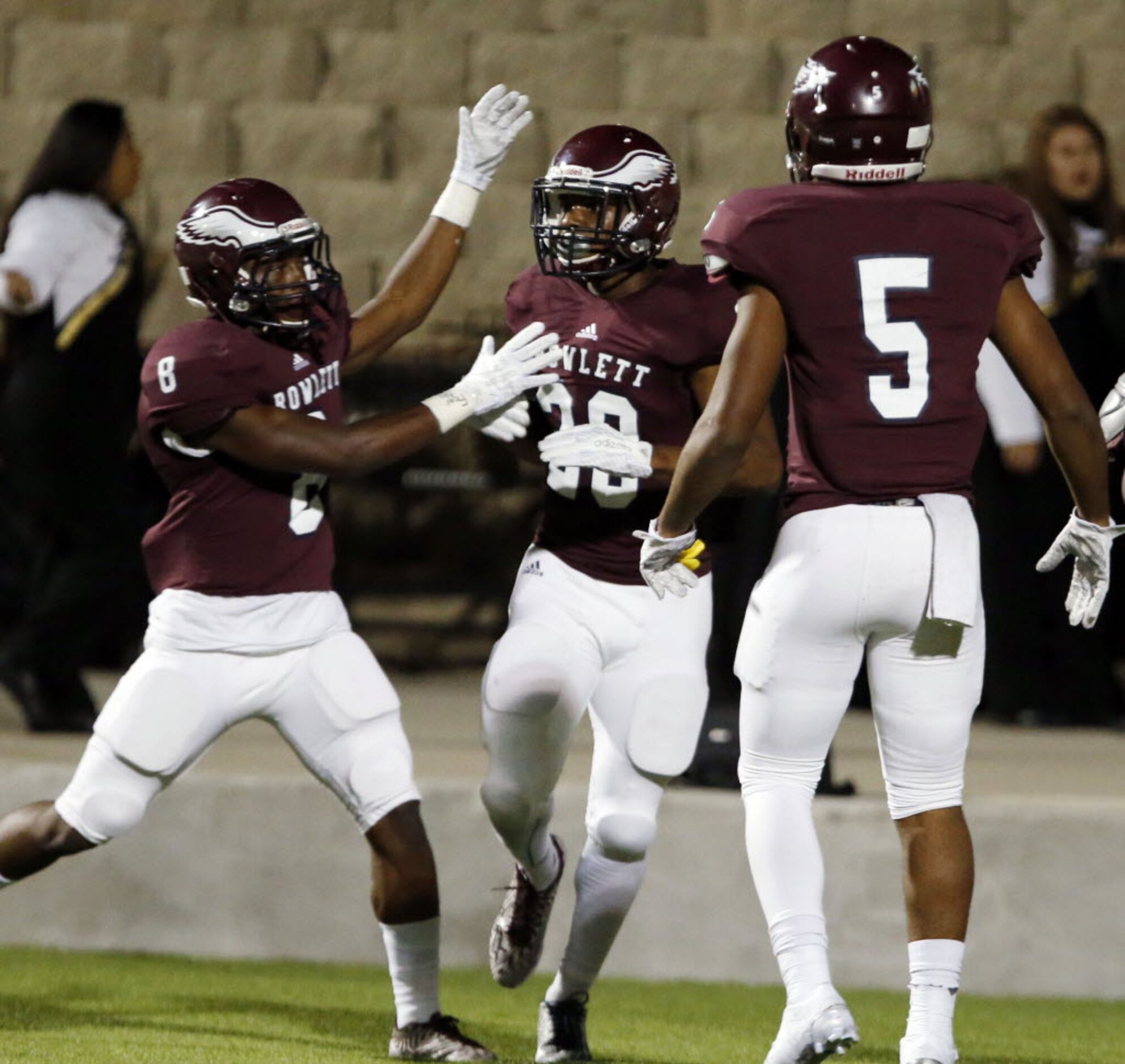 (TXHSFB) Rowlett WR LaDarius Dickens (20) celebrates with teammates Quinton Stinson (8) and...