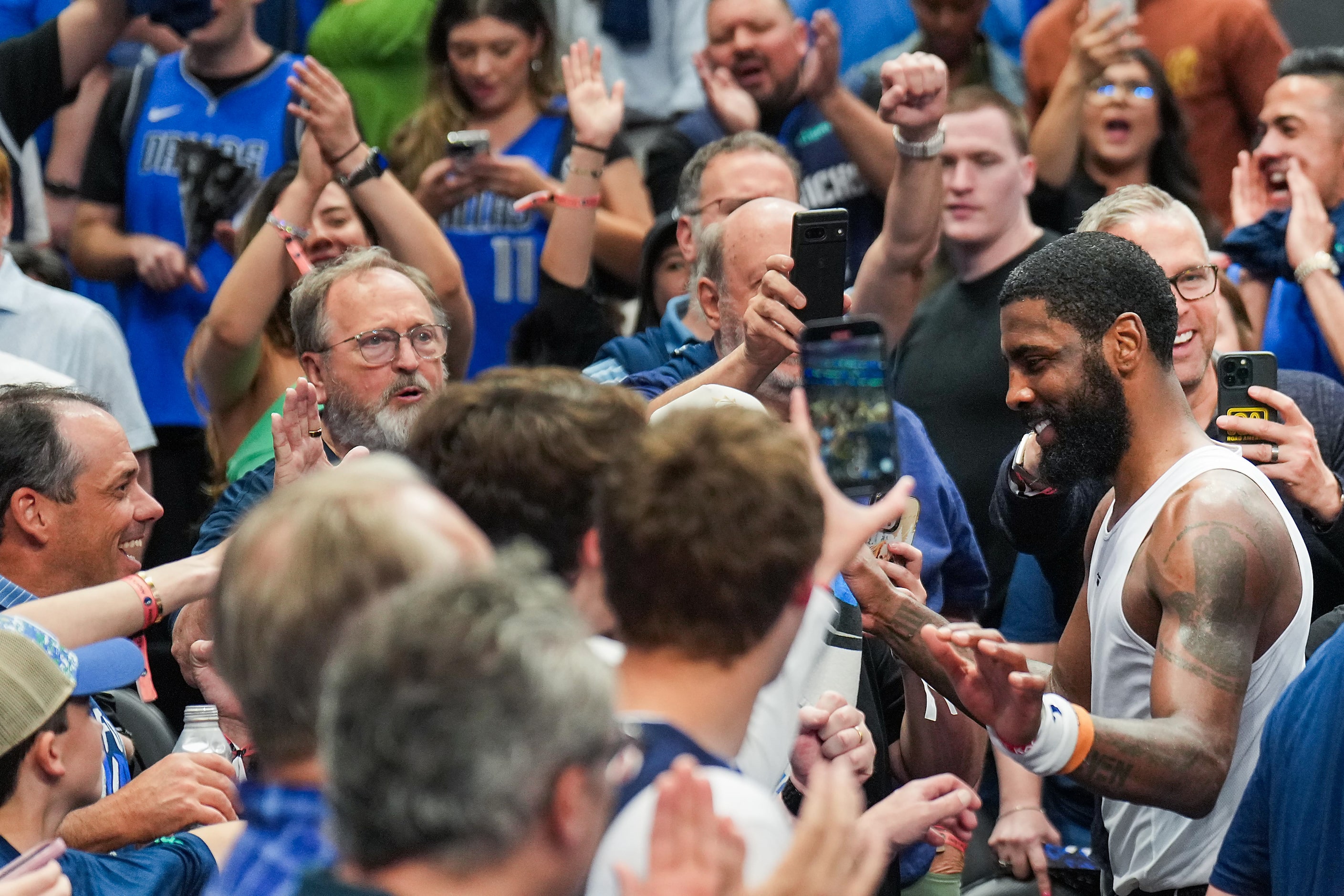 Dallas Mavericks guard Kyrie Irving slaps hands with fans as he leaves the court after a...