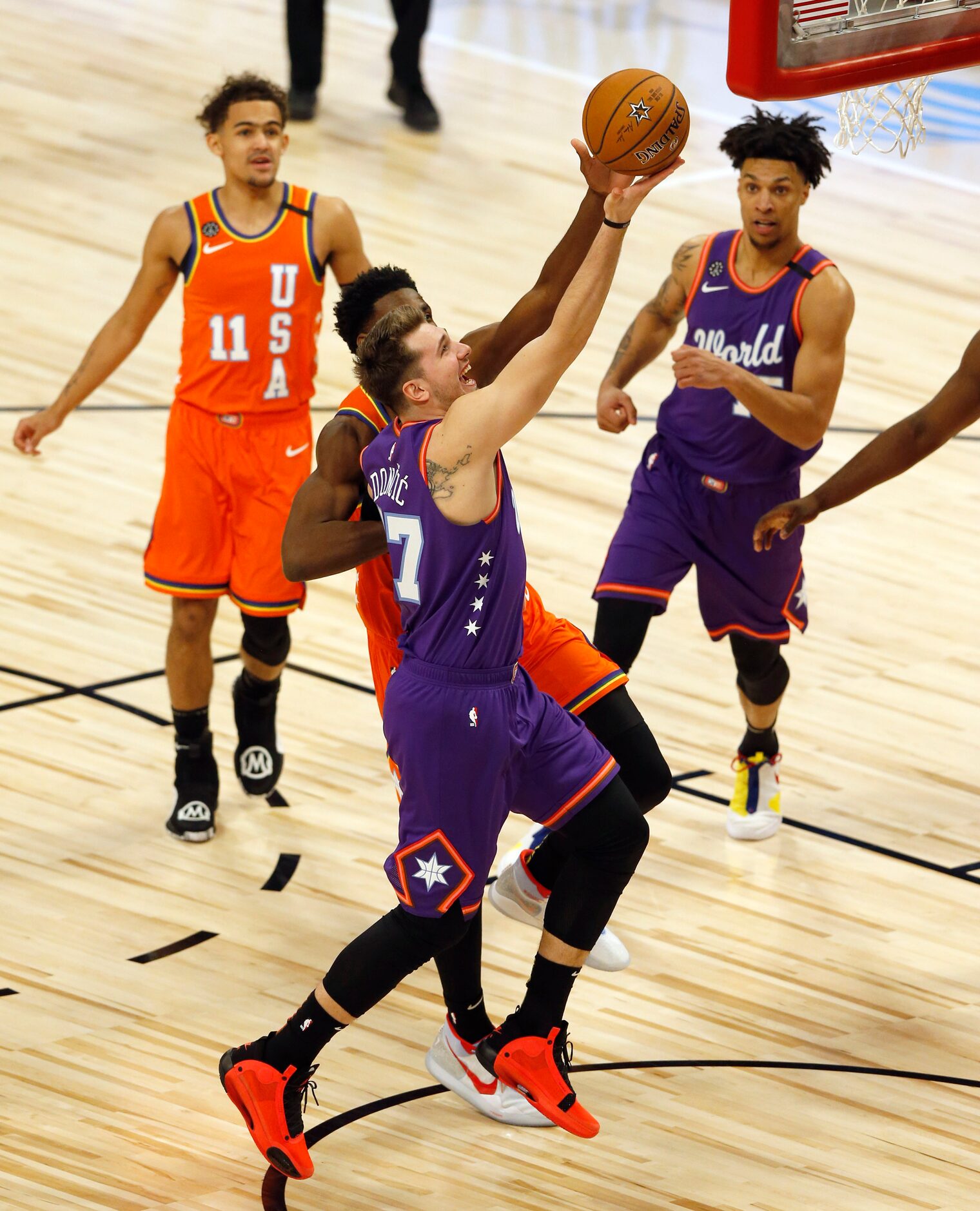 World Team and Dallas Mavericks Luka Doncic (77) attempts a layup in front of USA Team and...