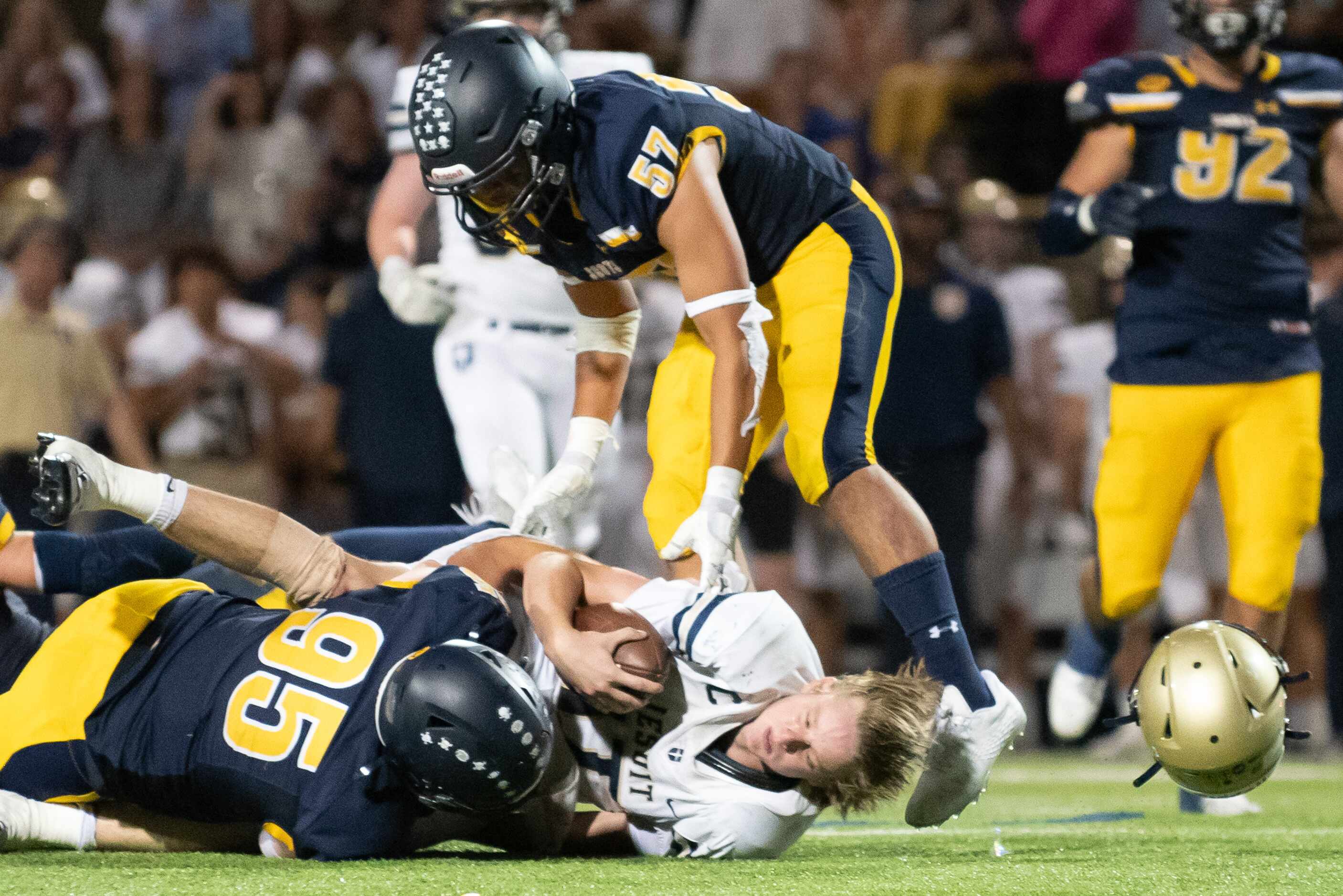Jesuit senior quarterback Charlie Schmidt (17) loses his helmet as he's tackled after a run...