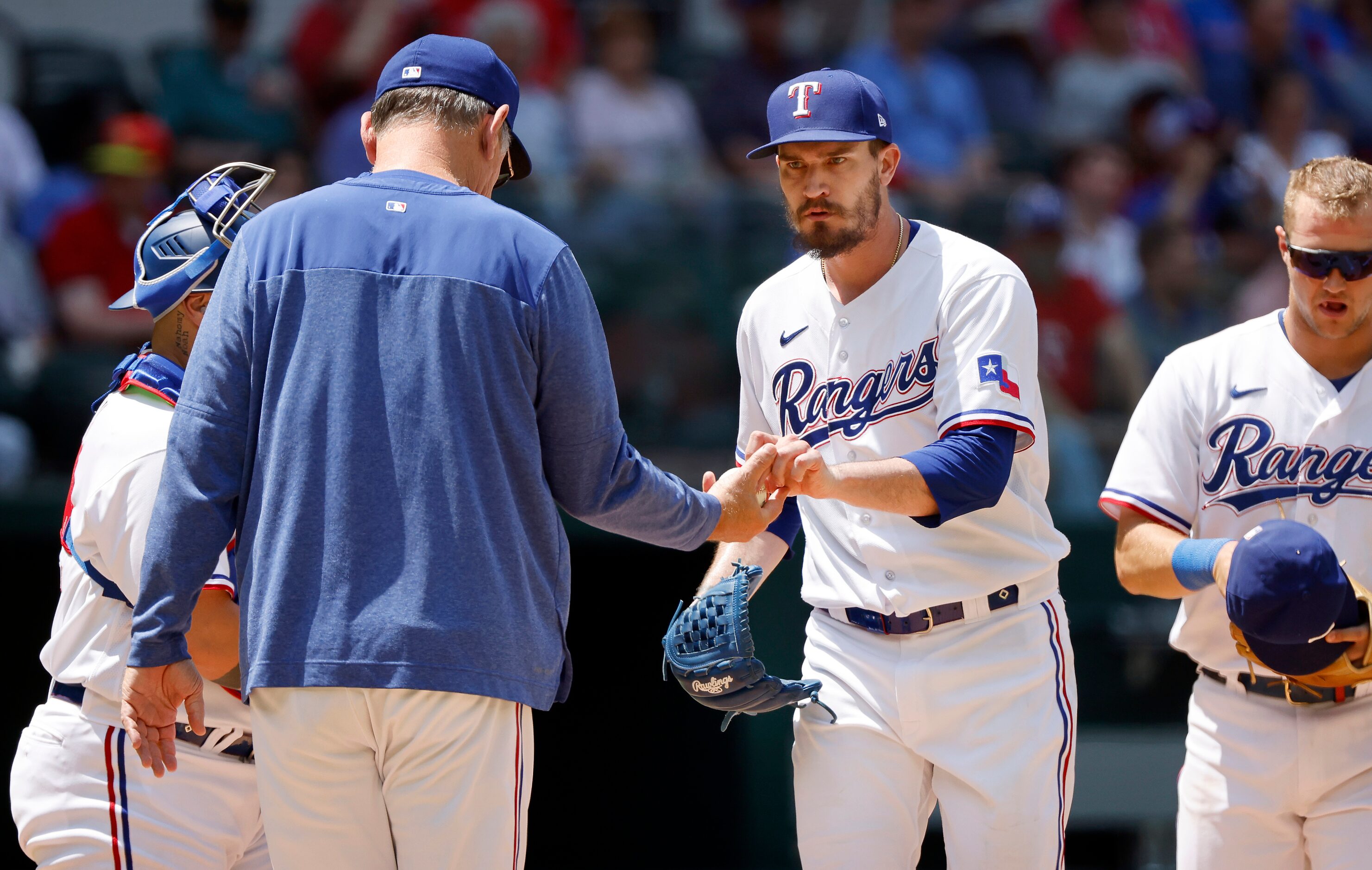 Texas Rangers starting pitcher Andrew Heaney (center) hands the ball off to manager Bruce...